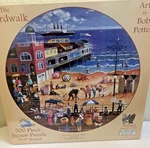 Sunsout The Boardwalk Bob Pettes 500 Jigsaw Puzzle 19.5 Inch Round Nib. Fixed Price $24.99.